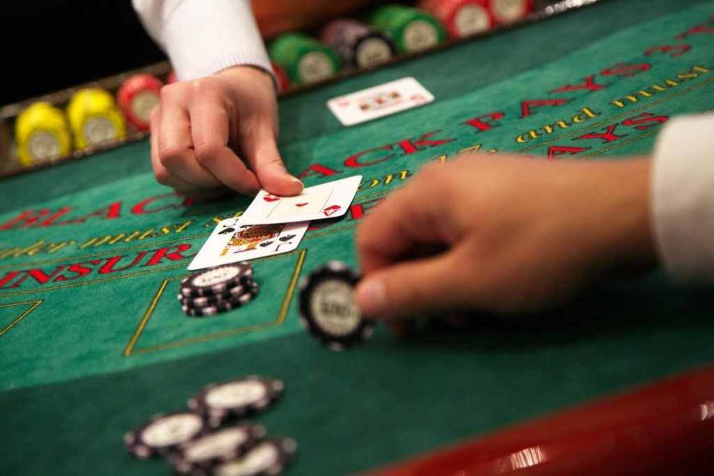 Dealer hands out 2 cards to a player who is placing chips on the green table