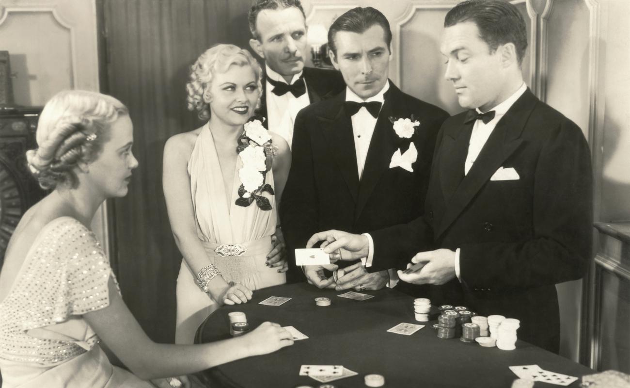 black and white photograph of three men and two women playing poker