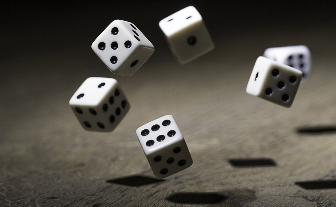 6 white and black dice bouncing in a dark atmosphere on a wooden surface.