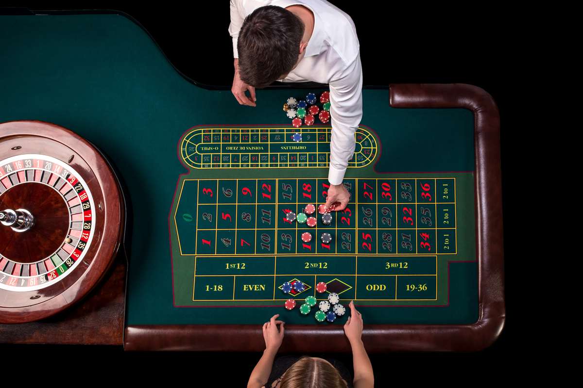 Male dealer handing out chips to a woman playing roulette on a green table