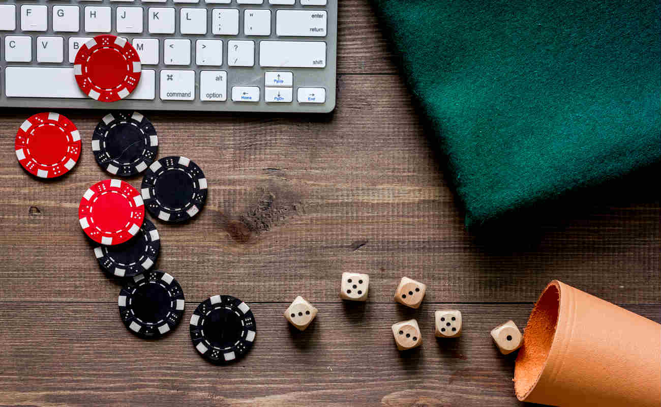 Online poker. Chips and the dice nearby keyboard on wooden table top view copyspace