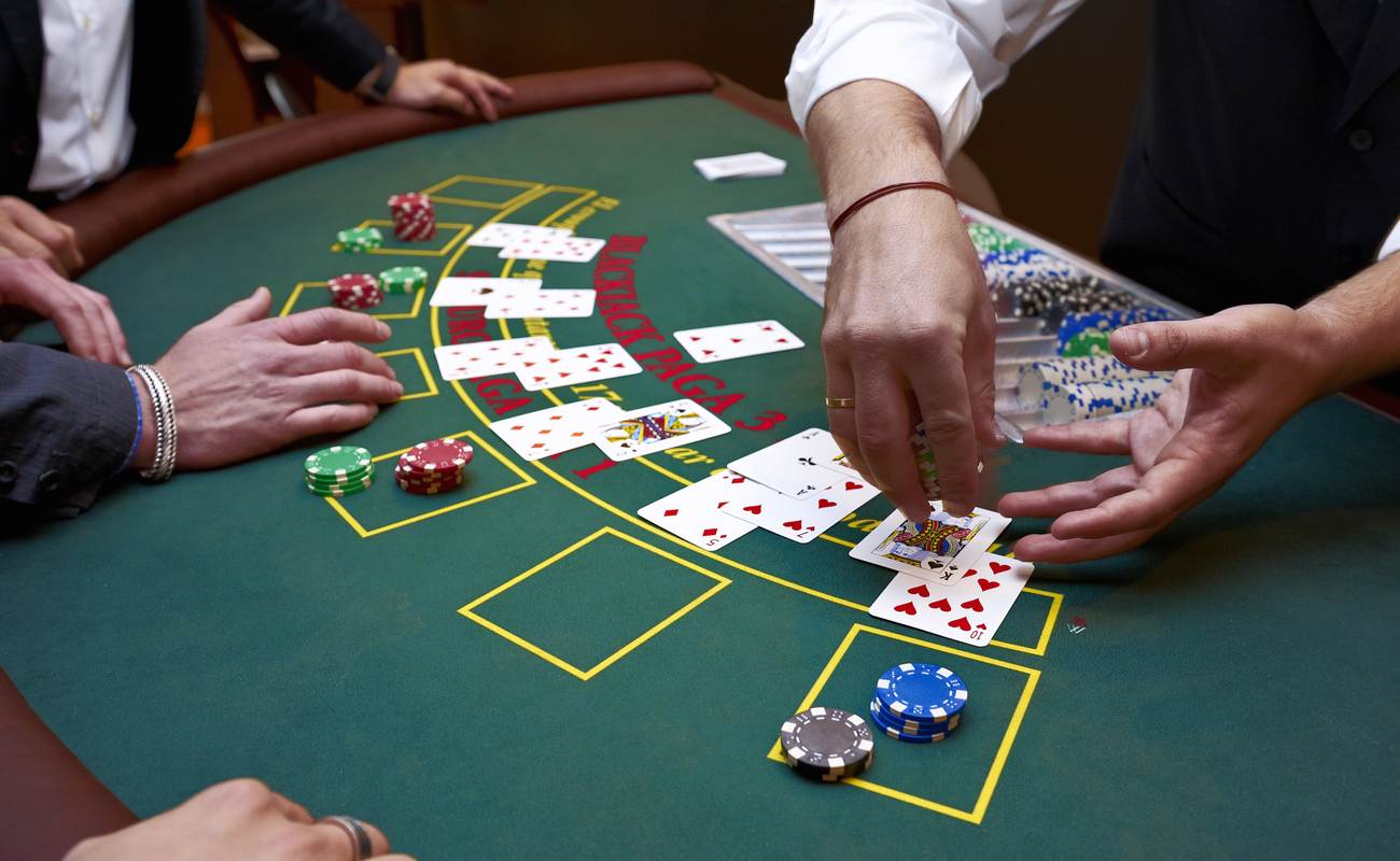 A close up of a blackjack dealer's hands in a casino, cards and chips