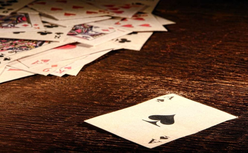 Ace Of Spades playing card and stack of antique poker game cards on wooden table