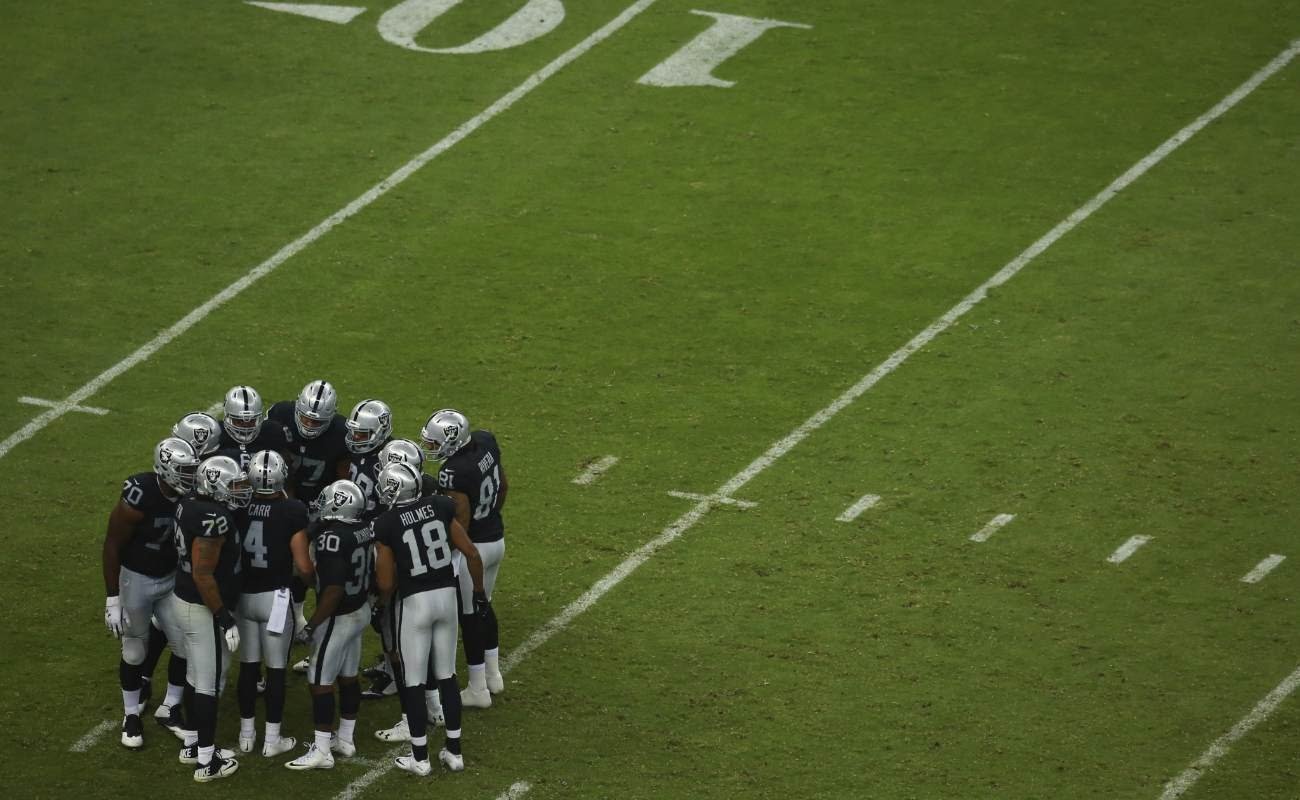 Oakland Raiders team huddle on the field.
