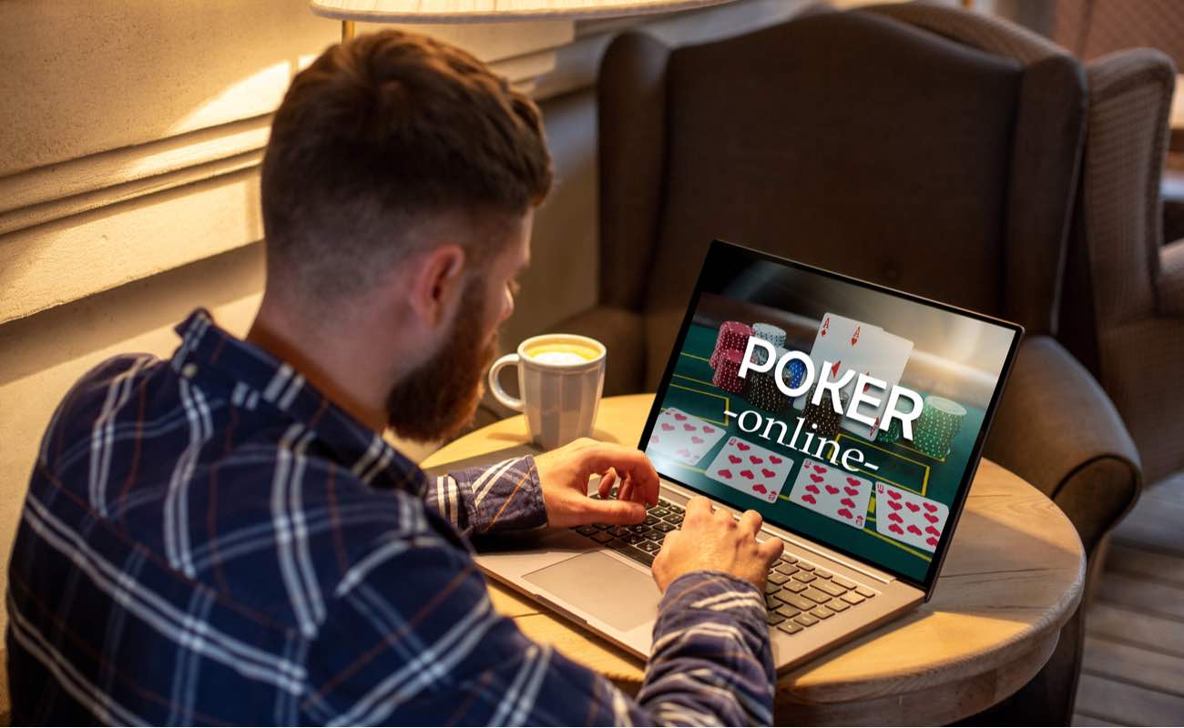Young man playing poker online on a laptop with coffee