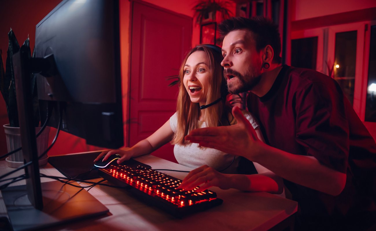 A man and woman are amazed while playing PC games