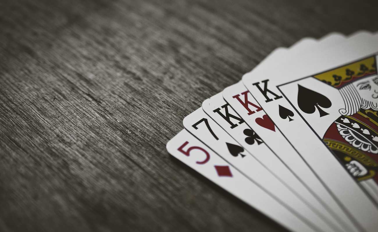 Playing cards laid out as a poker hand on a wooden grey table.