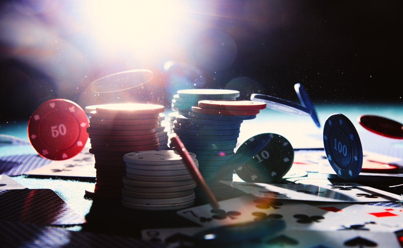 Digital render of stacks of poker chips with playing cards scattered on a casino table.