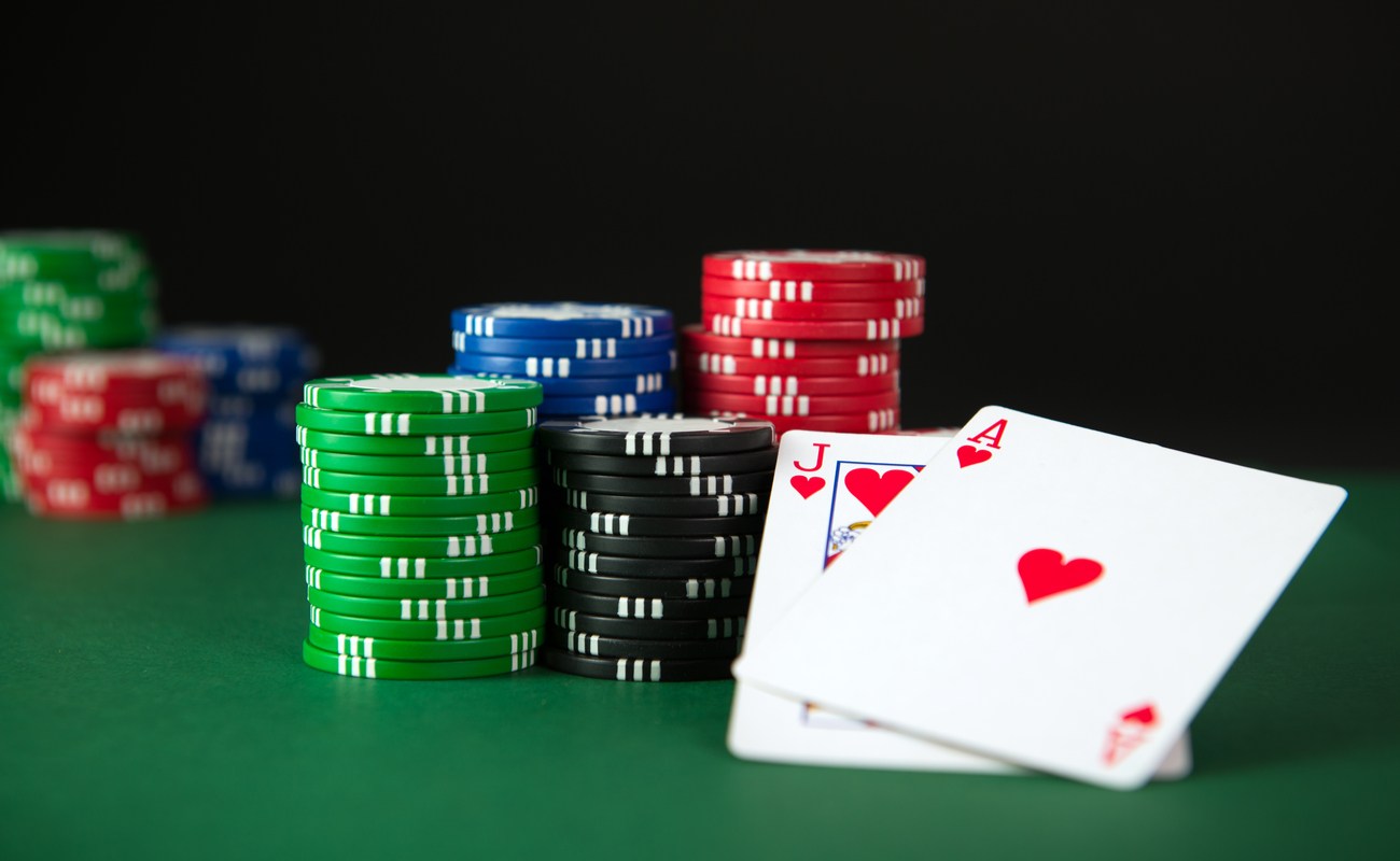 A jack and ace of hearts sit next to stacks of casino chips on a green table.