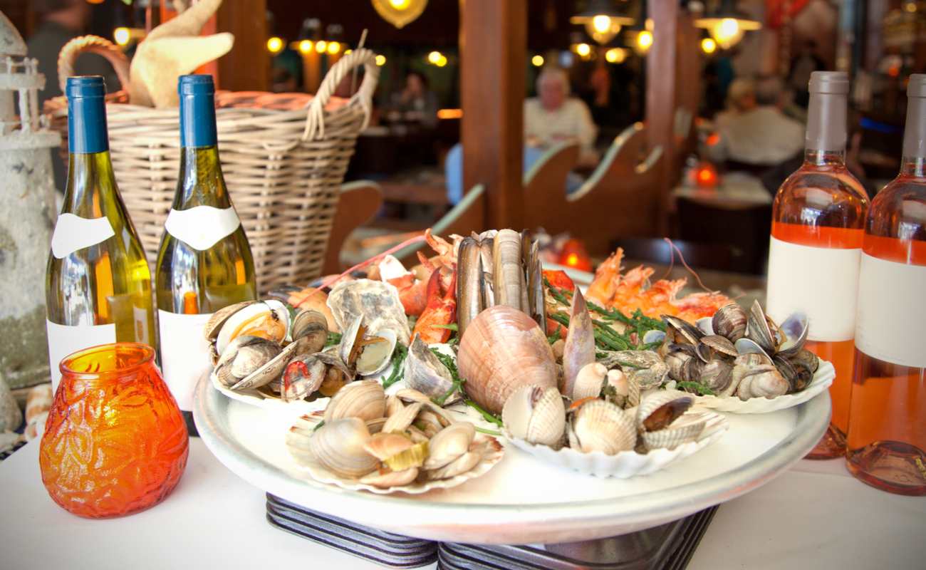 A platter of seafood on a table next to bottles of wine.