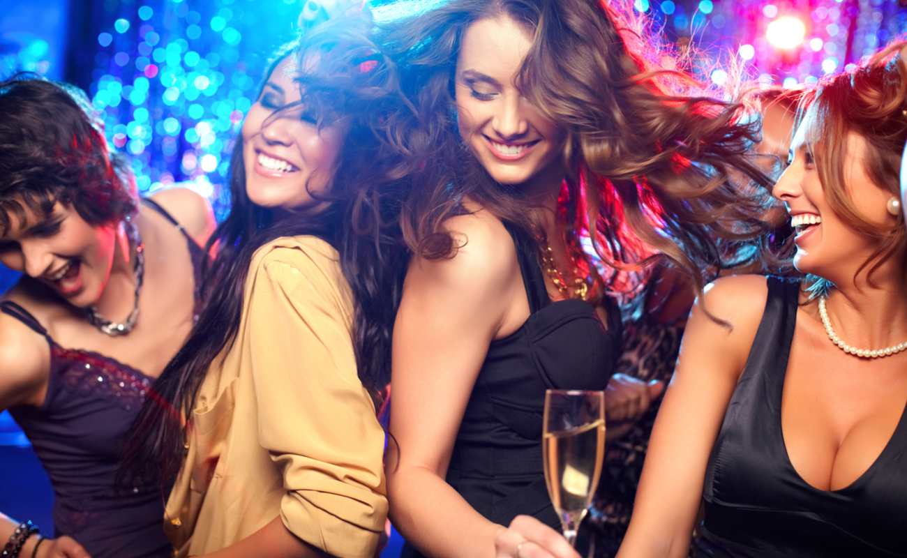 Four women drinking and dancing at a nightclub.