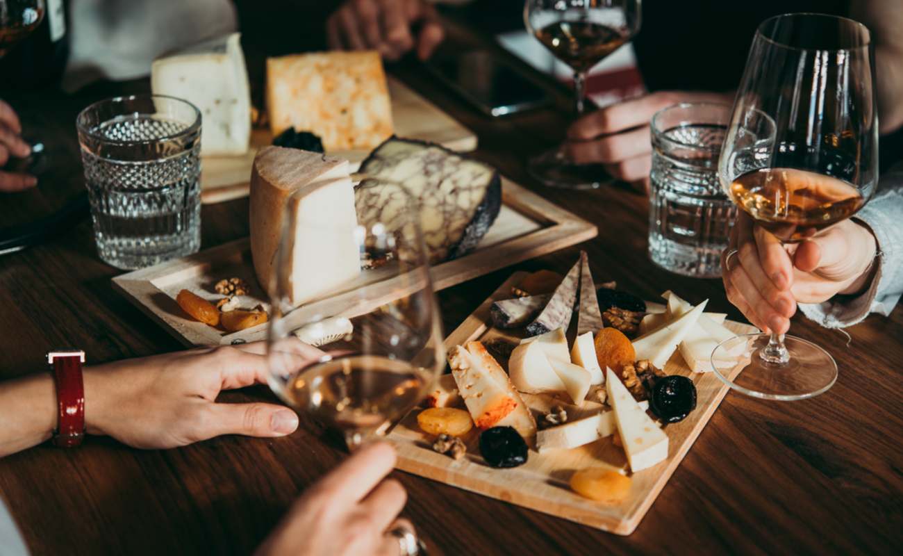 People sharing a French cheese starter with a few glasses of wine.