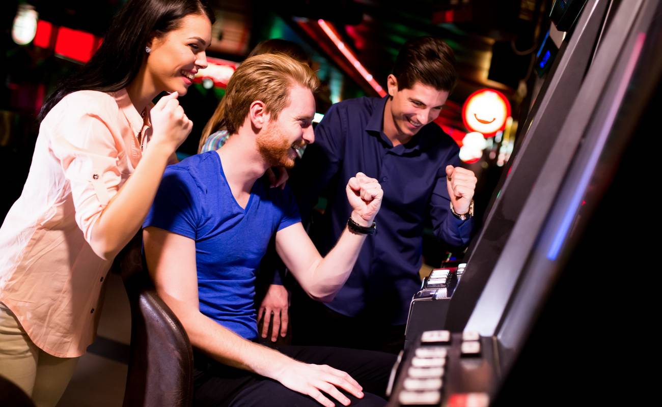 A group of friends cheer after a win at a slot machine.