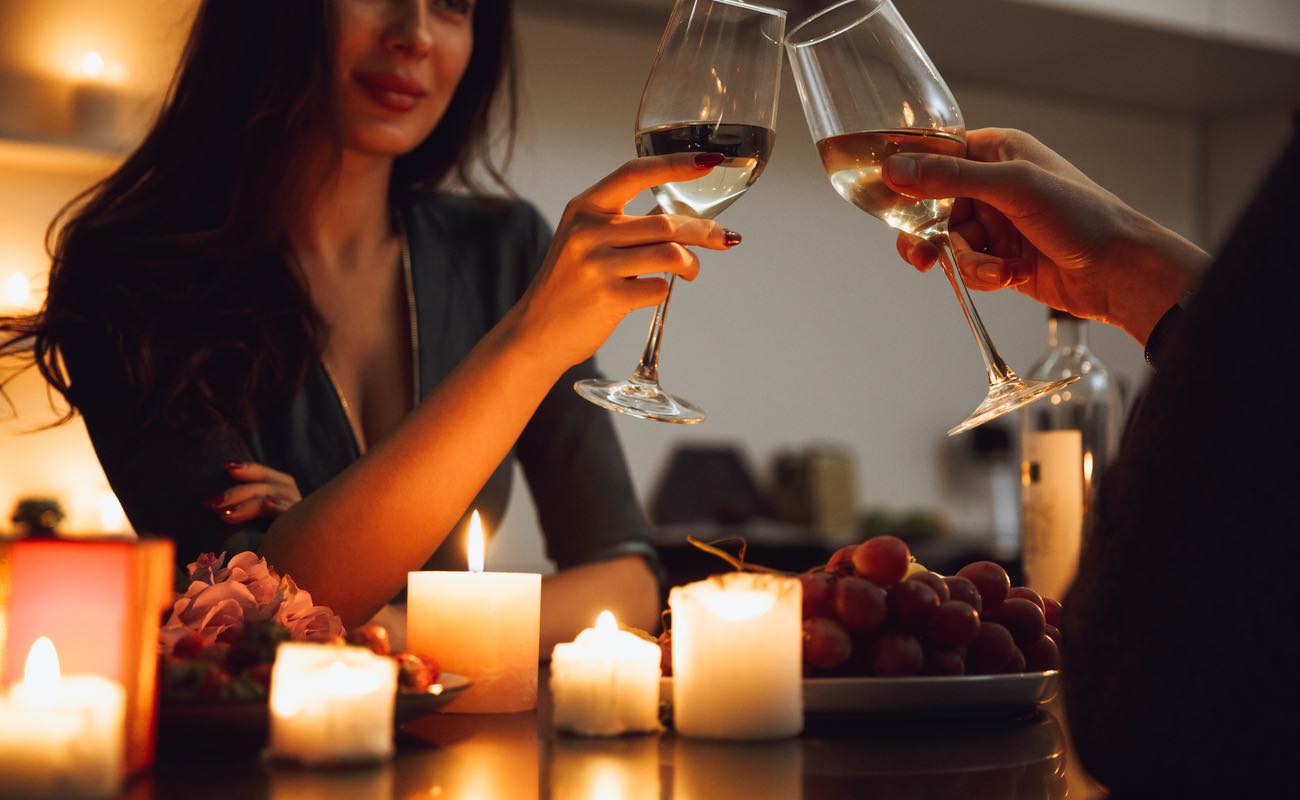 A couple having a romantic candlelight dinner at home, drinking wine, toasting.