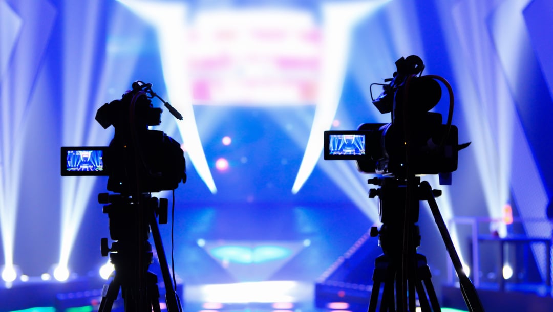 Silhouette of two cameras with studio lights in the background.