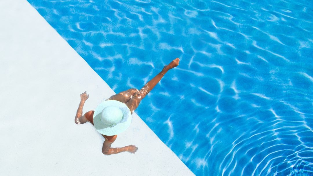 A woman relaxes at the side of a luxury pool.