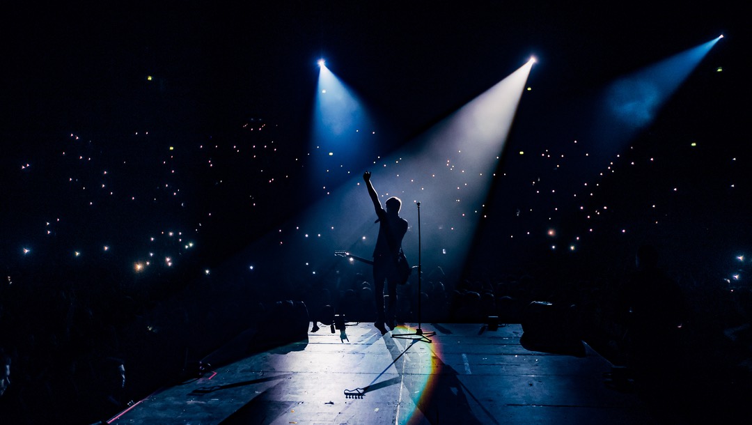 Silhouette of a musician playing to a crowd.