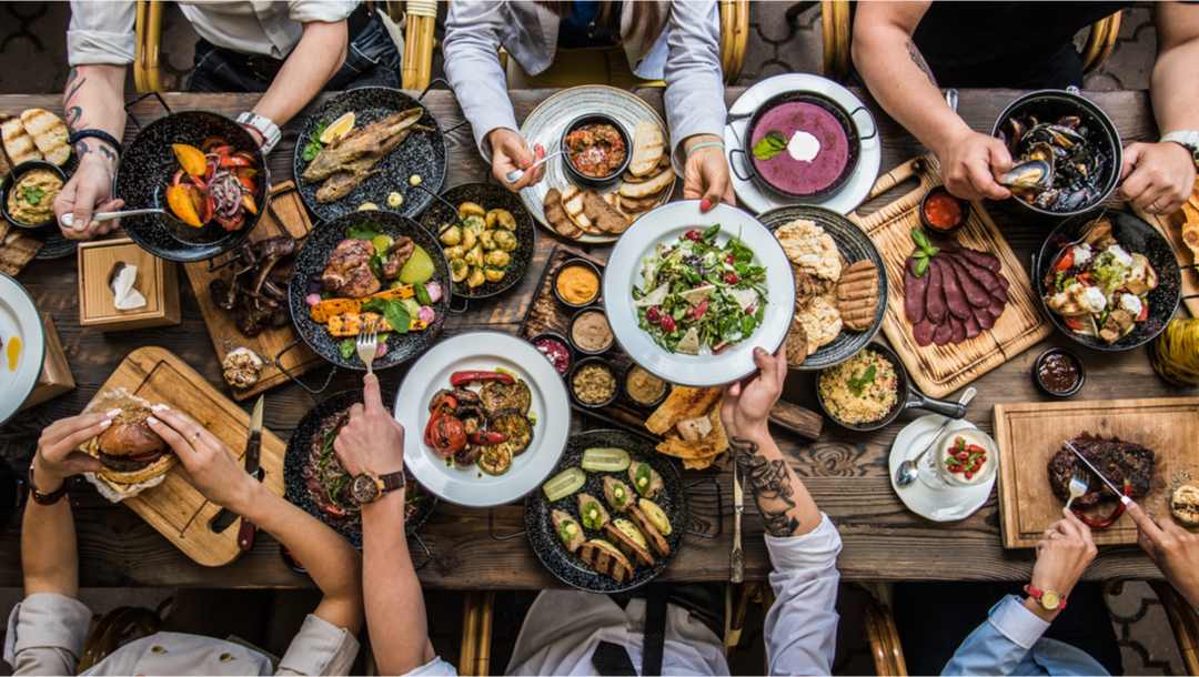 A group of people at a table eating a variety of food.