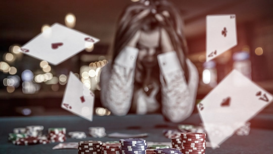 A woman holds her head in her hands while aces fly onto a gambling game table.