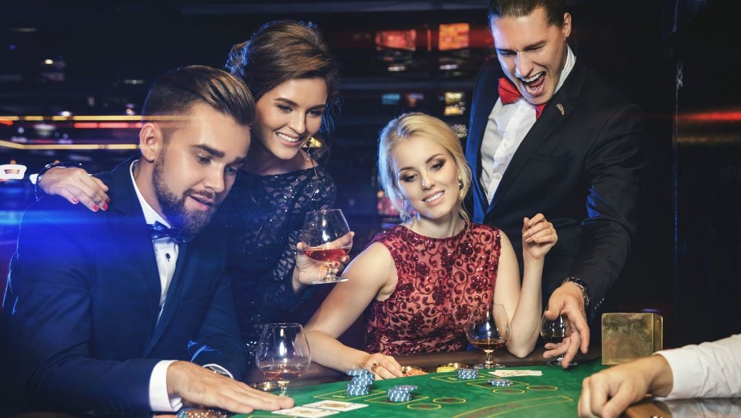 four people sitting at a poker table playing blackjack