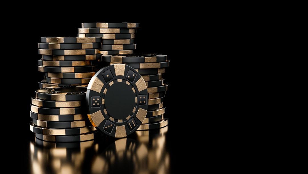 A large stack of modern gold and black casino chips.