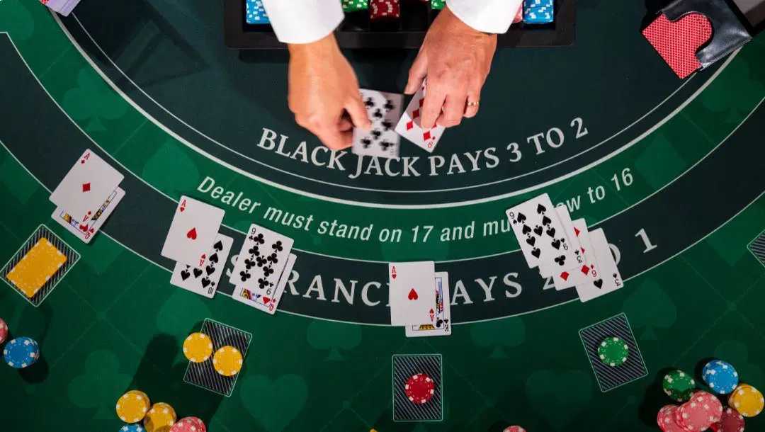 An aerial view of a blackjack dealer as they place down the dealer cards. All the player cards are already on the blackjack table.