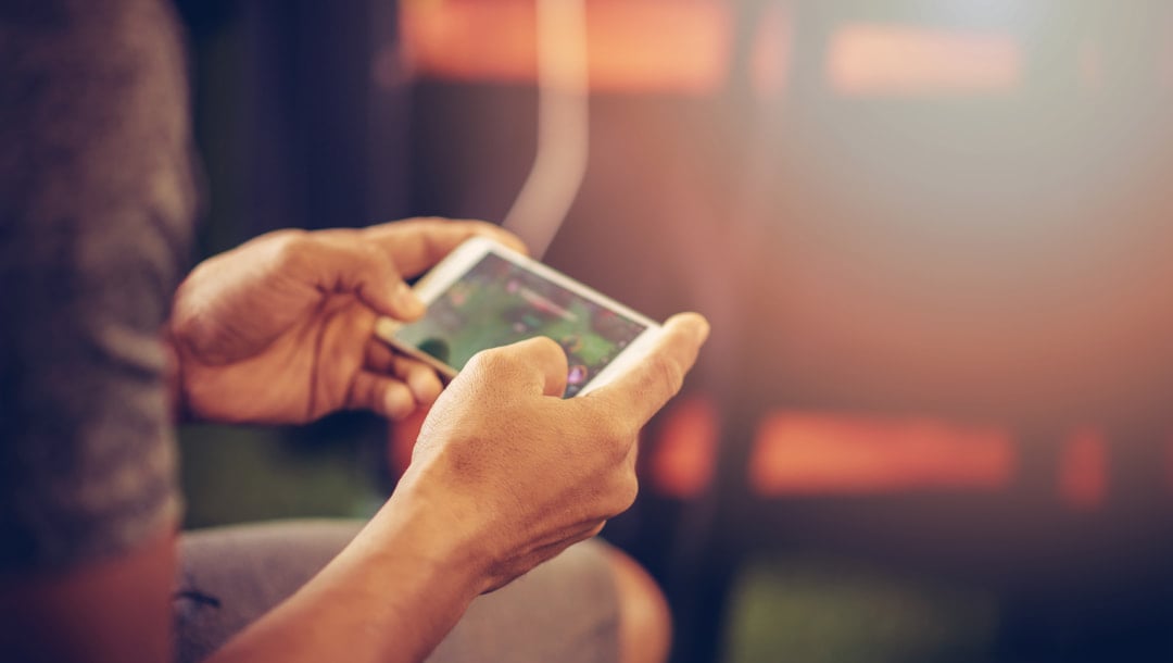 A man playing games on a smartphone. The background is distorted with an orange light.