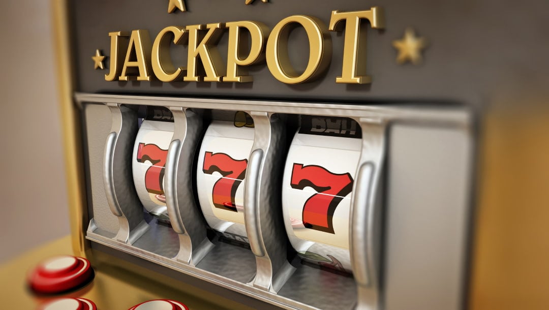 An old slot machine with three reels containing the number seven. The word jackpot is written in gold above the reels.