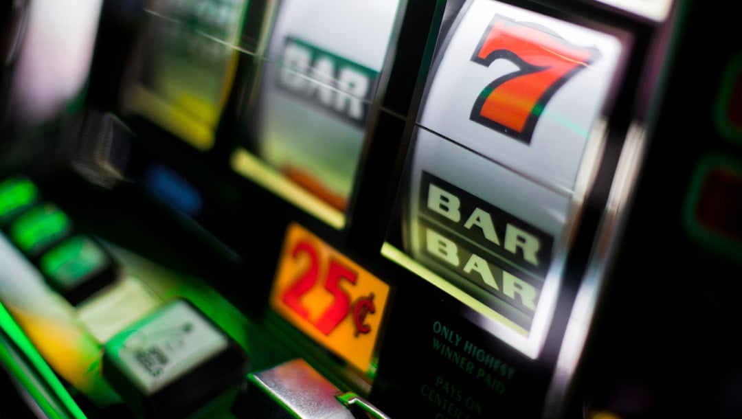 A slot machine with classic symbols such as the bar and the red number seven. There is a 25c sign below the reels. The slot machine is black and silver.