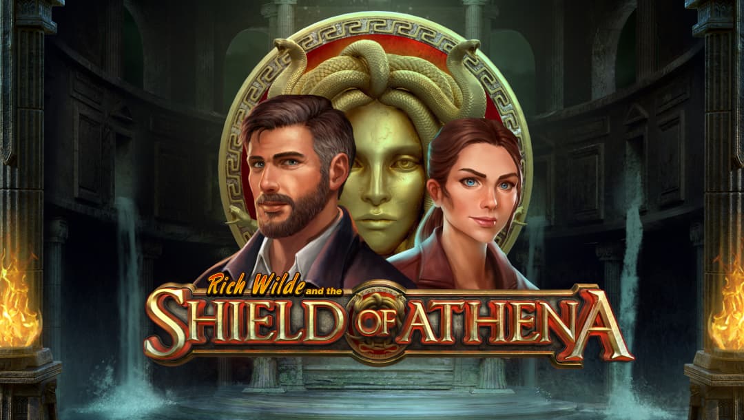 A screenshot of the title screen of Rich Wilde and the Shield of Athena, featuring Rich and Cat Wilde in front of the Shield of Athena, a red shield with Medusa’s face on it.