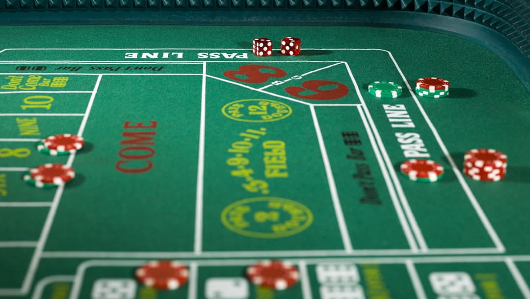 A green felt craps table with casino chips and red dice on it.