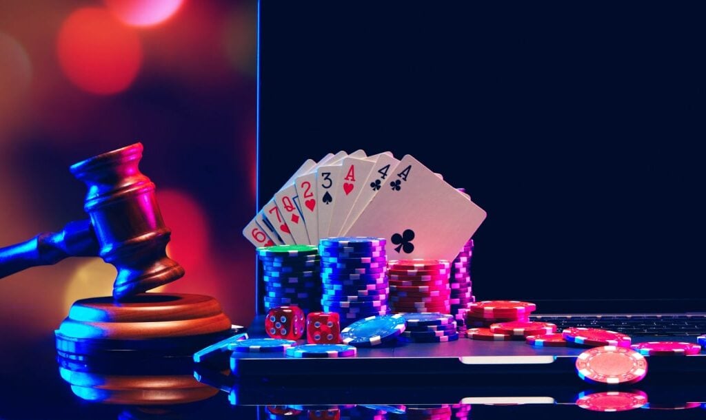 A gavel, playing cards, dice, and casino chips arranged on a table.