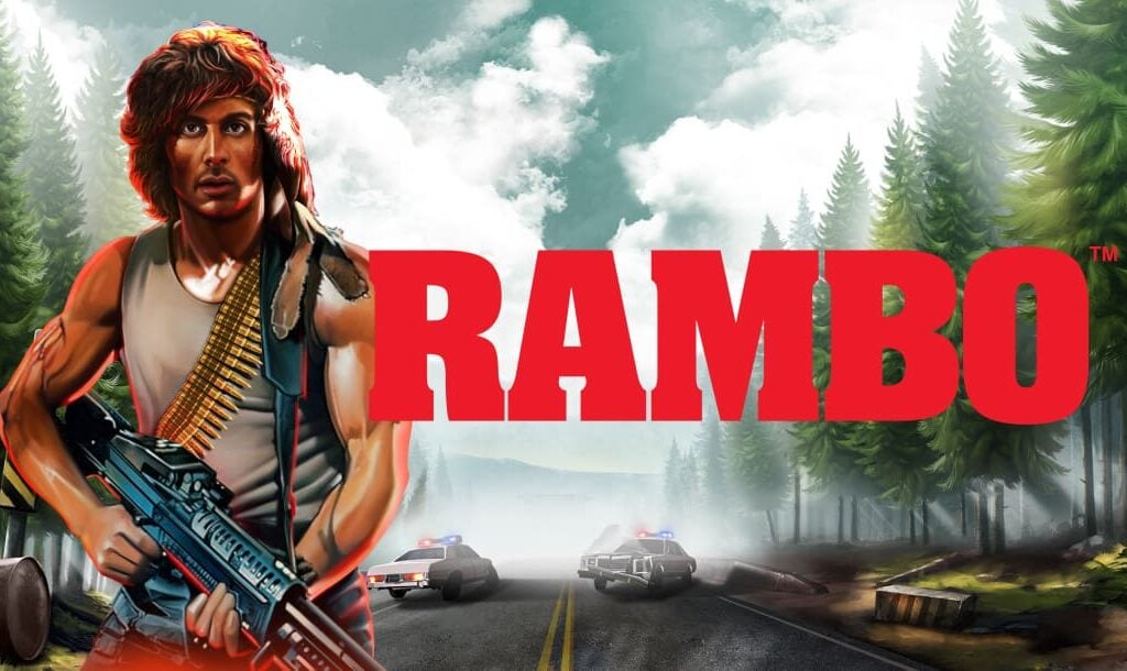 The Rambo online slot loading screen featuring the game and movie title, Rambo, and a scene in the background featuring a road in between a forest and two cop cars in the road.